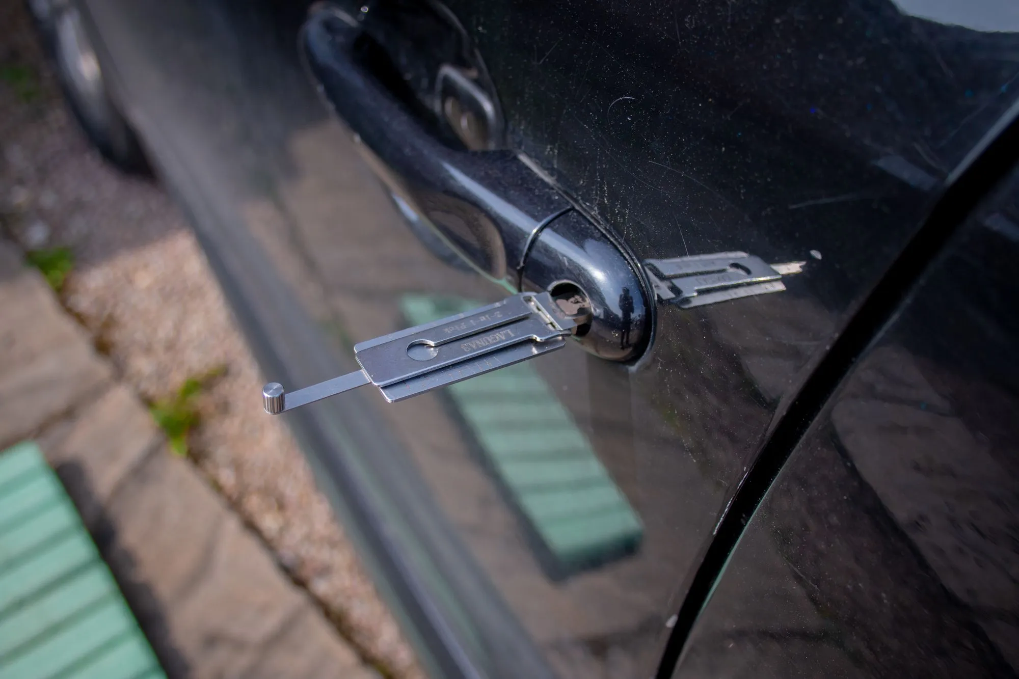 Automotive locksmith unlocking a car door lock with professional tools