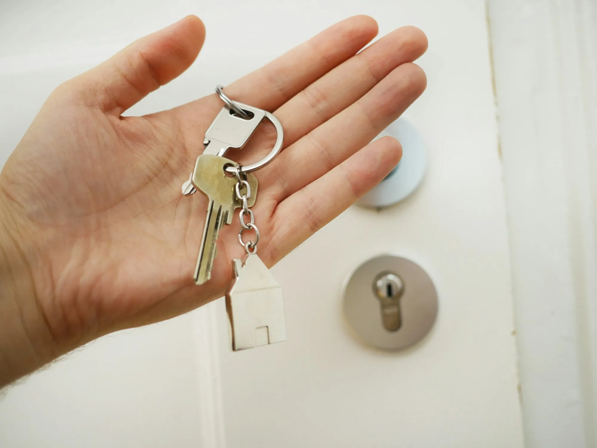 Homeowner holding house keys in front of a front door deadbolt